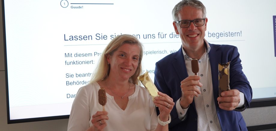 Eisaktion PG Landrat Christian Engelhardt und Gesine Johannsen, Mitarbeiterin der Abteilung Moderne Verwaltung, E-Government und IT, halten ein Eis in die Kamera.