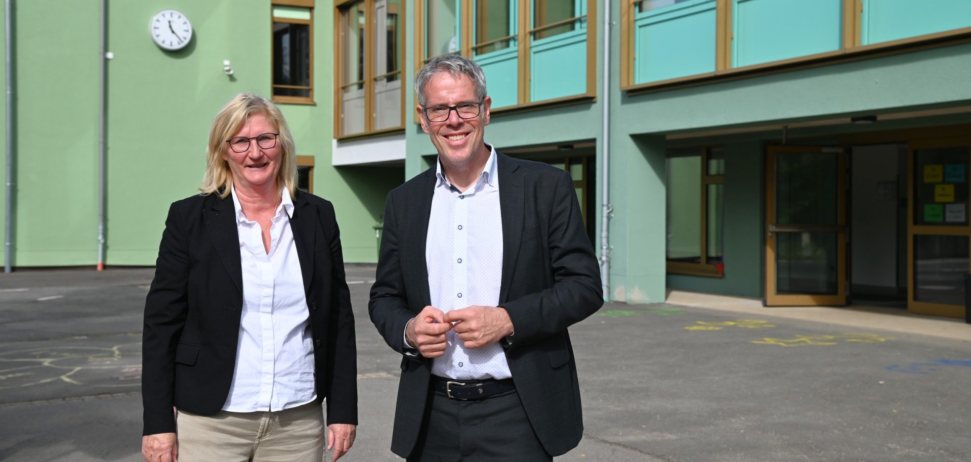 Schulleiterin Silke Jendrzejewski und Landrat Christian Engelhardt begutachten die letzten Baumaßnahmen auf dem Schulhof.