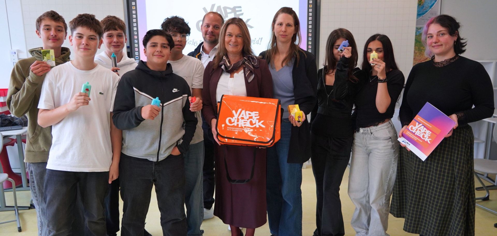Die Erste Kreisbeigeordnete und Gesundheitsdezernentin Angelika Beckenbach, Schulleiter Thomas Rech, sowie Nicole Brosé und Klara Pohl von PRISMA mit Schülerinnen und Schülern der achten Klassen beim Vape-Check an der Langenbergschule Birkenau.