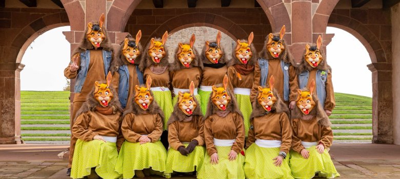 Gruppenbild der Lorscher Rabbits. 14 Personen mit braunen Pullover, grünen Röcken mit weißen Punkten und Masken mit Hasengesichtern. 