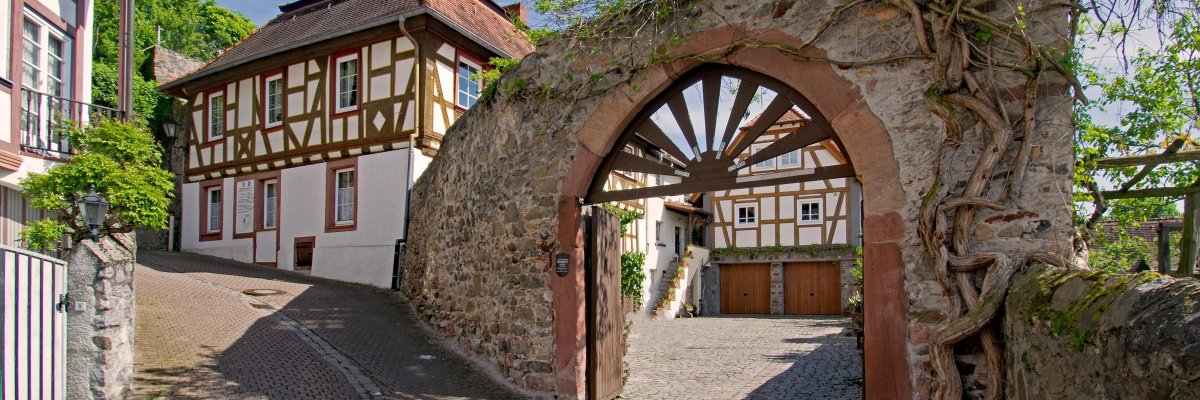 Die ALtstadt von Zwingenberg mit altem Mauertorbogen und Fachwerkhäusern unter blauem Himmel.