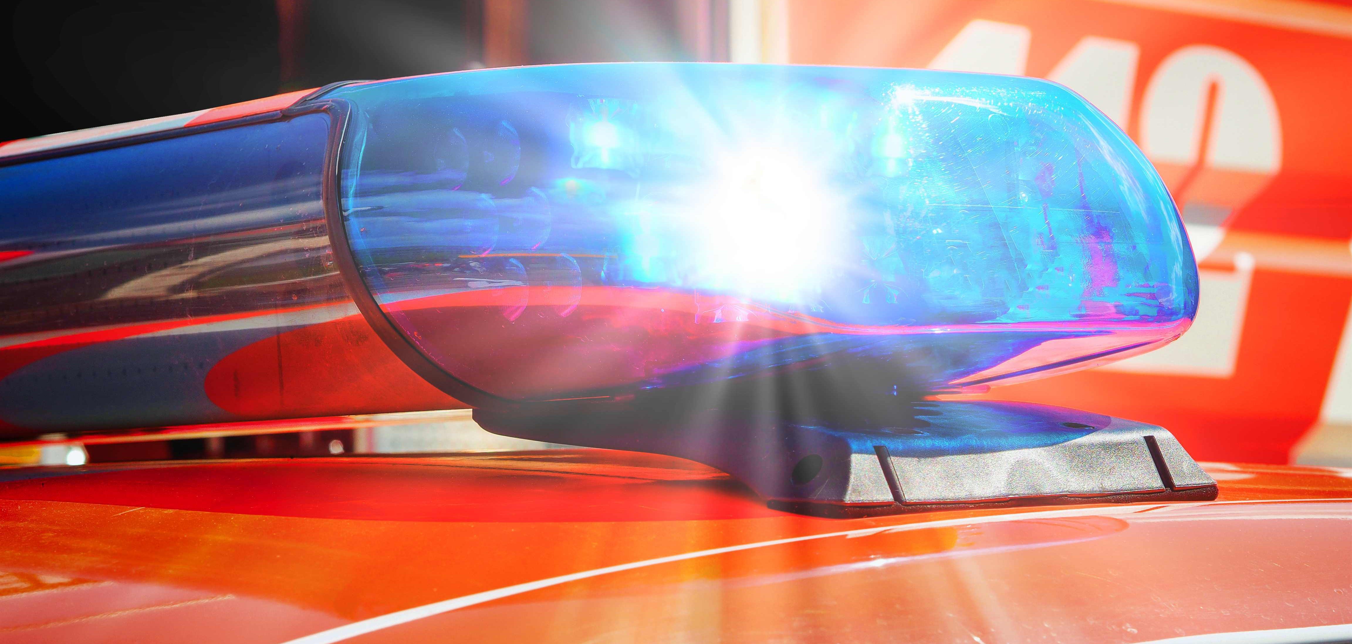 Das Dach eines roten Autos, auf dem ein Blaulicht blinkt.