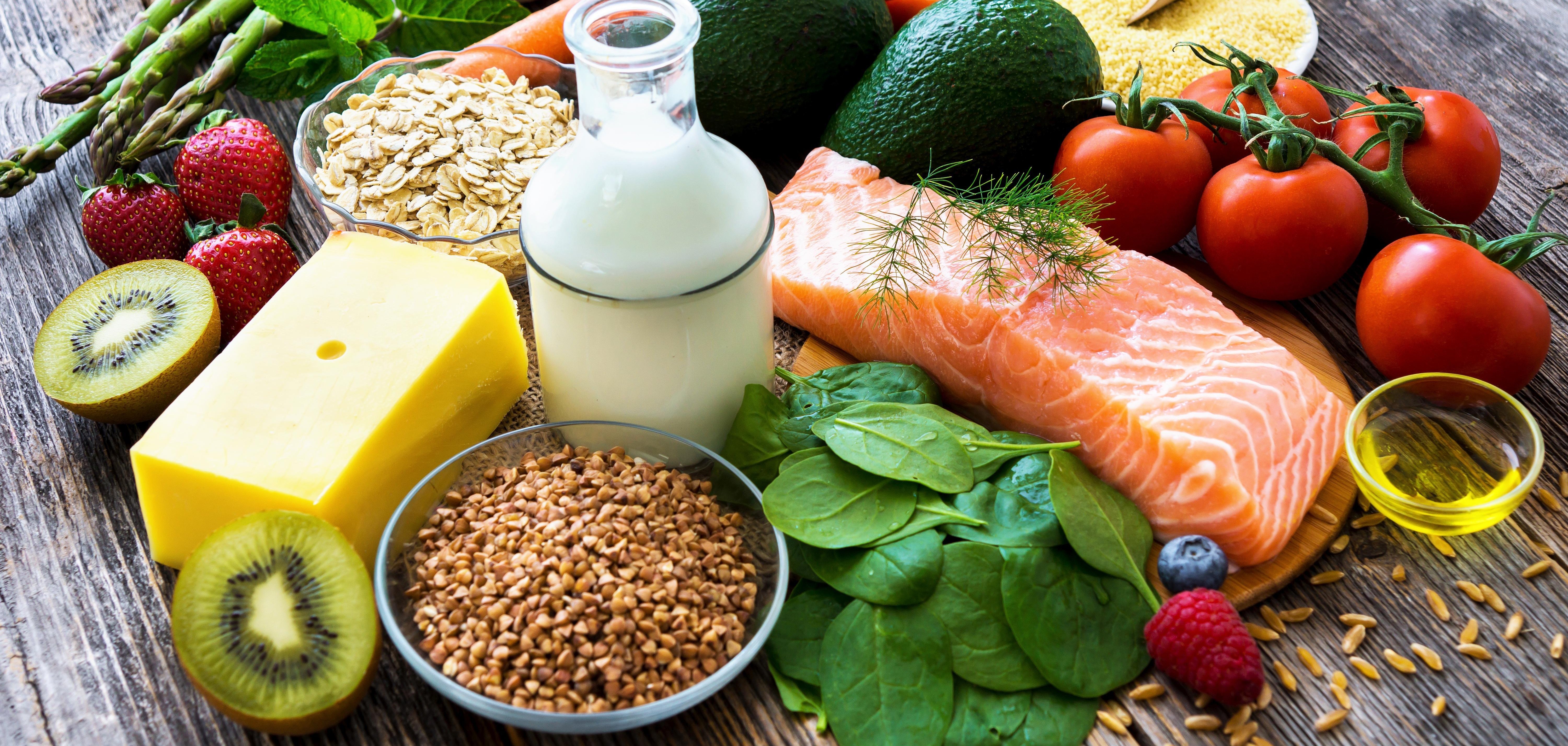 Eine Auswahl an gesundem Essen liegt auf einem Holzboden.