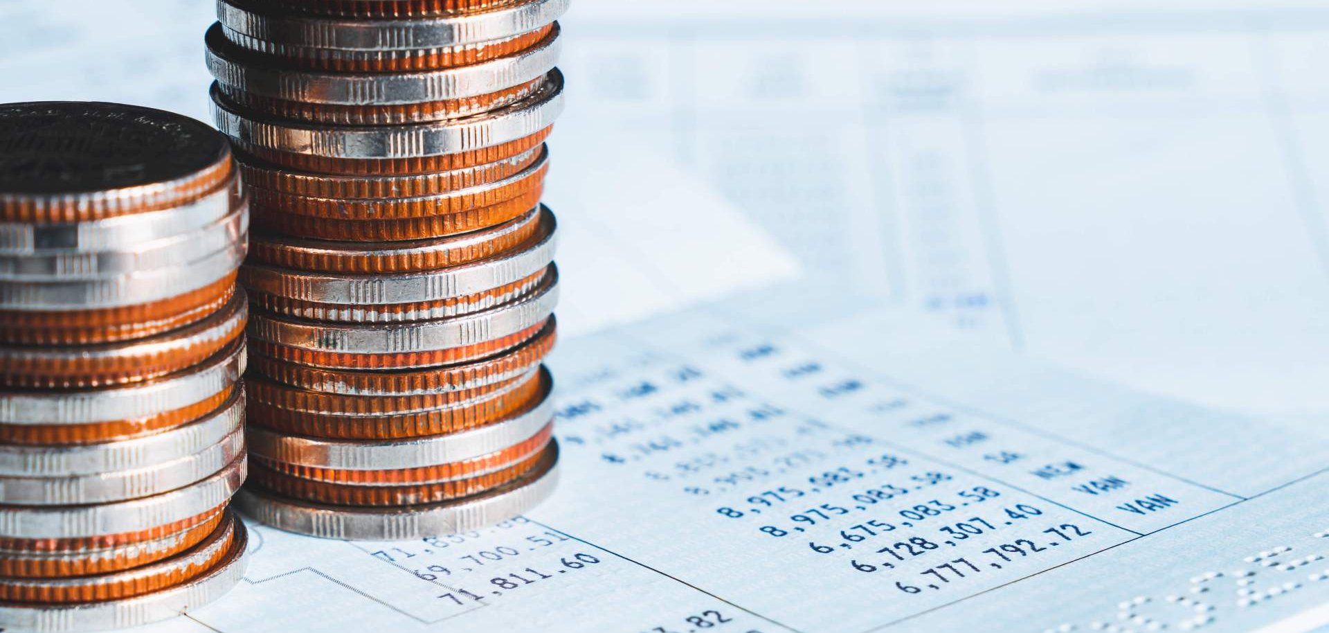 Zwei Stapel Münzen liegen auf Bankauszügen.