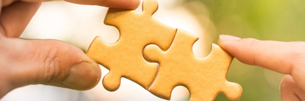 Hände halten passende Puzzleteile zusammen