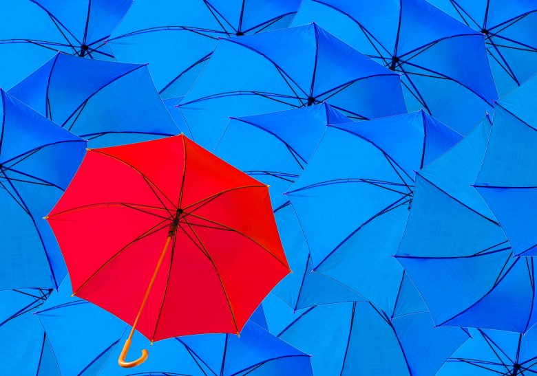 Aufgespannte blaue Regenschirme und ein roter Regenschirm