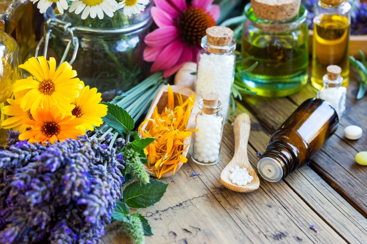 Naturheilkunde Heilpflanzen, Öle und Globulis stehen auf Holztisch