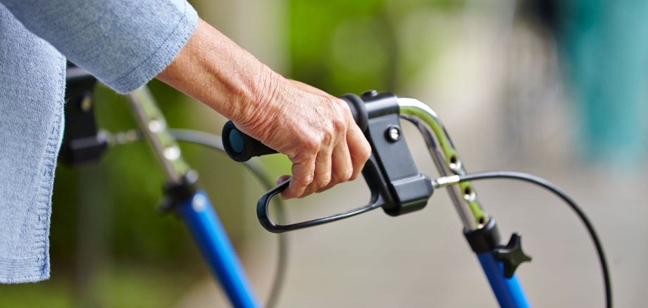 Hände eines Senioren am Griff eines Rollators