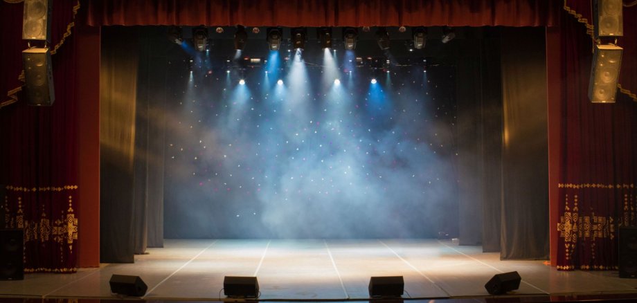 The stage of the theater illuminated by spotlights from the audi