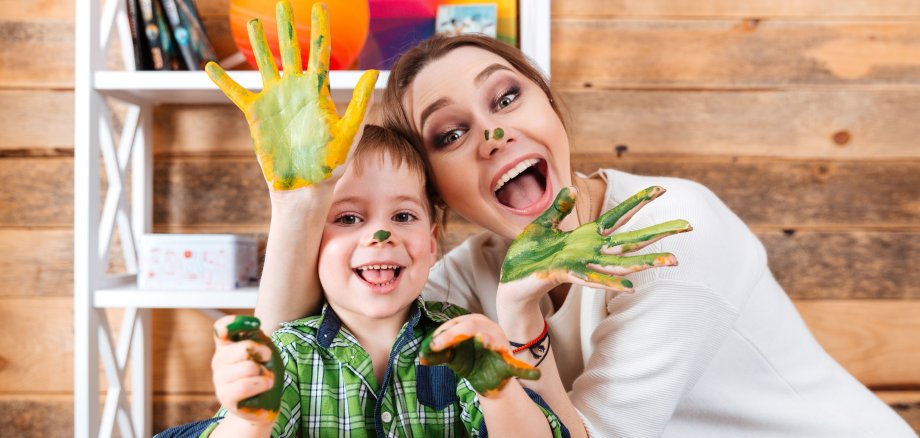 Cheerful mother and son with painted hands having fun together