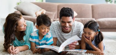 Parents and children lying on rug reading book