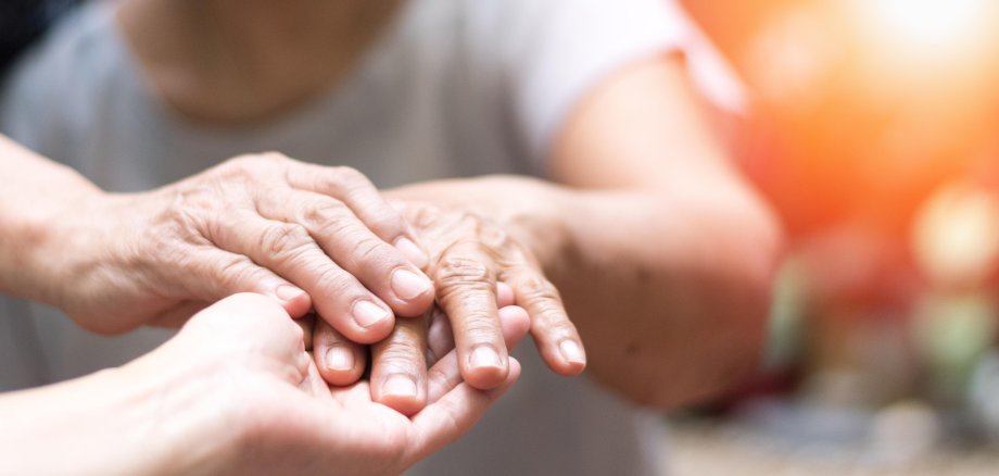 Caregiver, carer hand holding elder hand woman in hospice care.