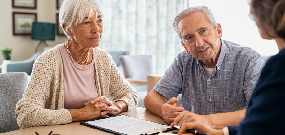 Eine Seniorin und ein Senior lassen sich von einer dritten Person beraten.