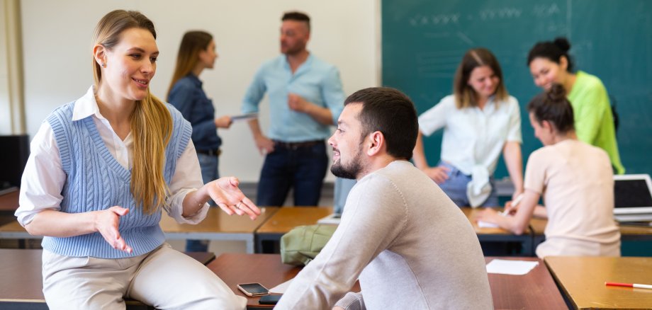 Man and woman students having small talk in classroom