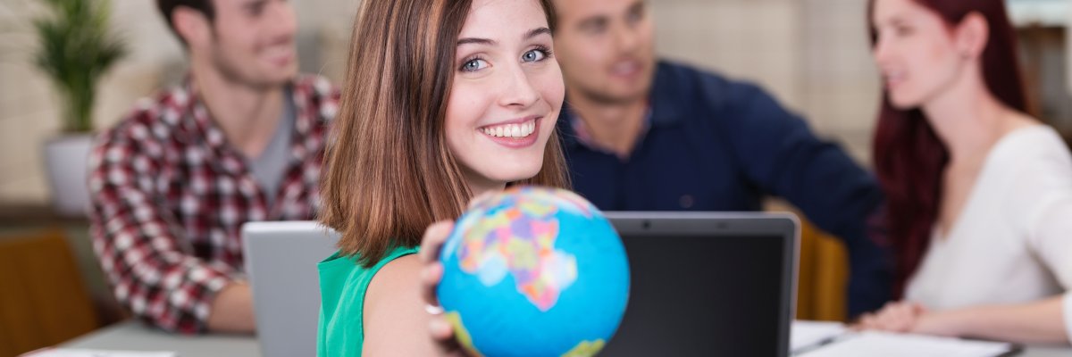 Junge Frau zeigt Weltkugel im Büro