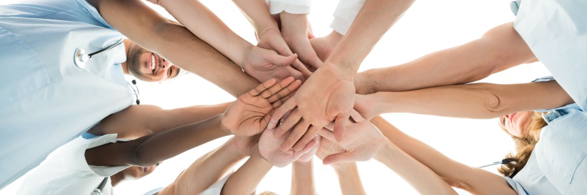 Arbeiter legen Hände aufeinander als Symbol der Teamarbeit