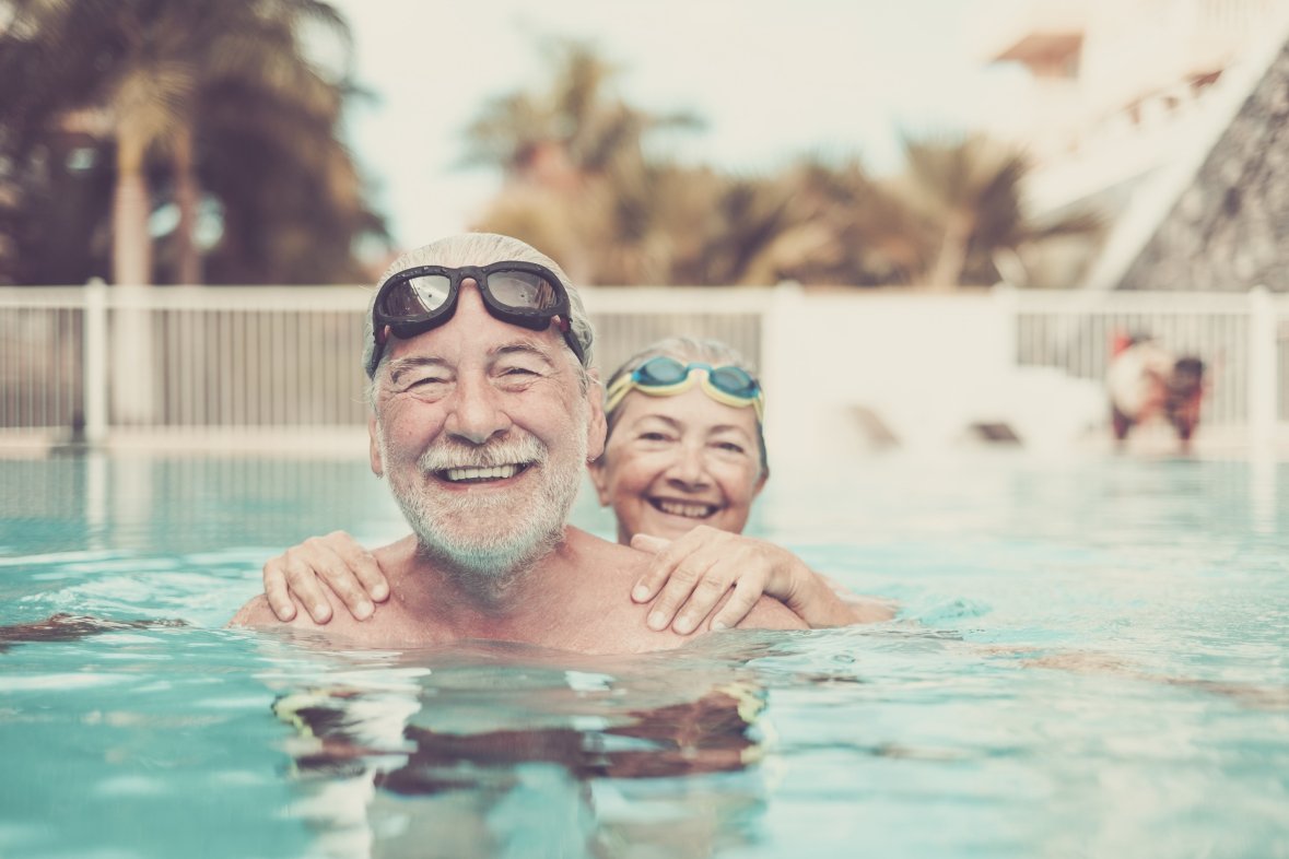 Senioren im Schwimmbad Glückliche Seniorin und Senior im Schwimmbad