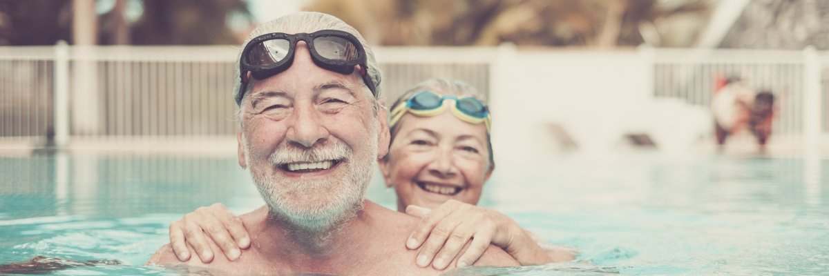 Senioren im Schwimmbad Glückliche Seniorin und Senior im Schwimmbad