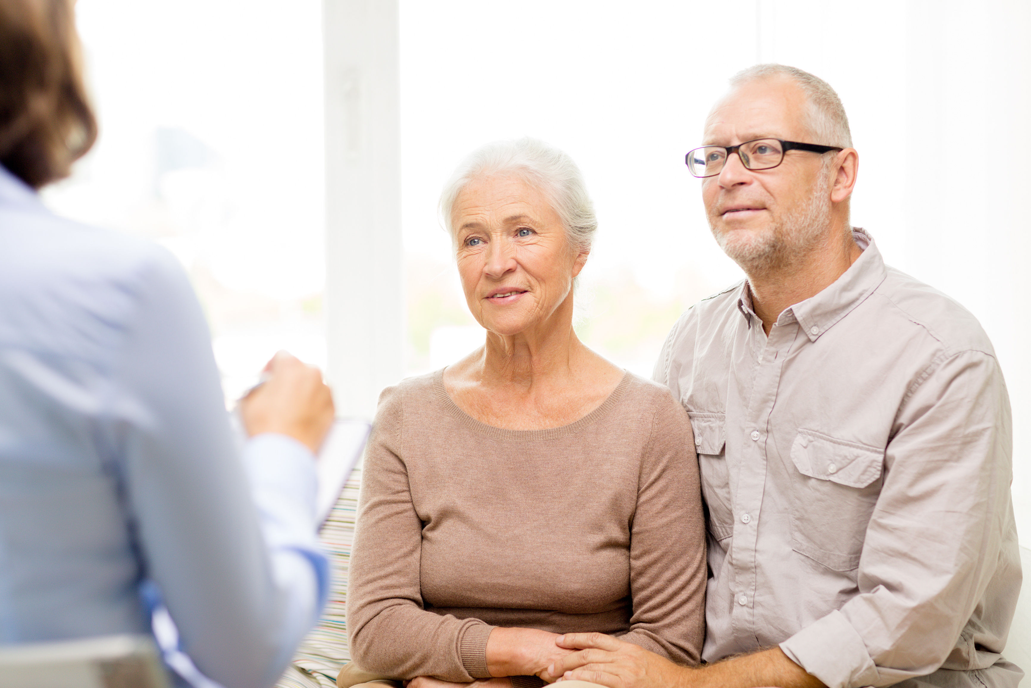 Eine Seniorin und ein Senior lassen sich von einer dritten Person beraten.