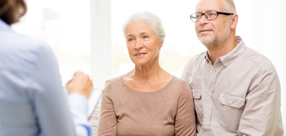 Eine Seniorin und ein Senior lassen sich von einer dritten Person beraten.