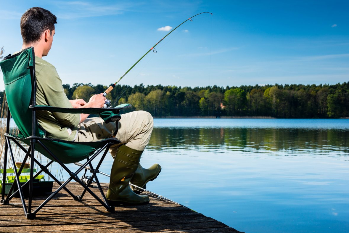 Mann angelt Mann sitz am Steg und fischt