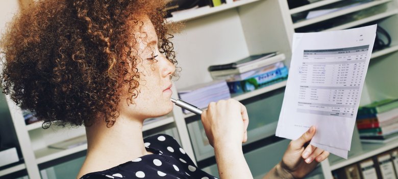 Junge Mitarbeiterin bei der Arbeit Junge Mitarbeiterin schaut sich Plan bei der Arbeit an