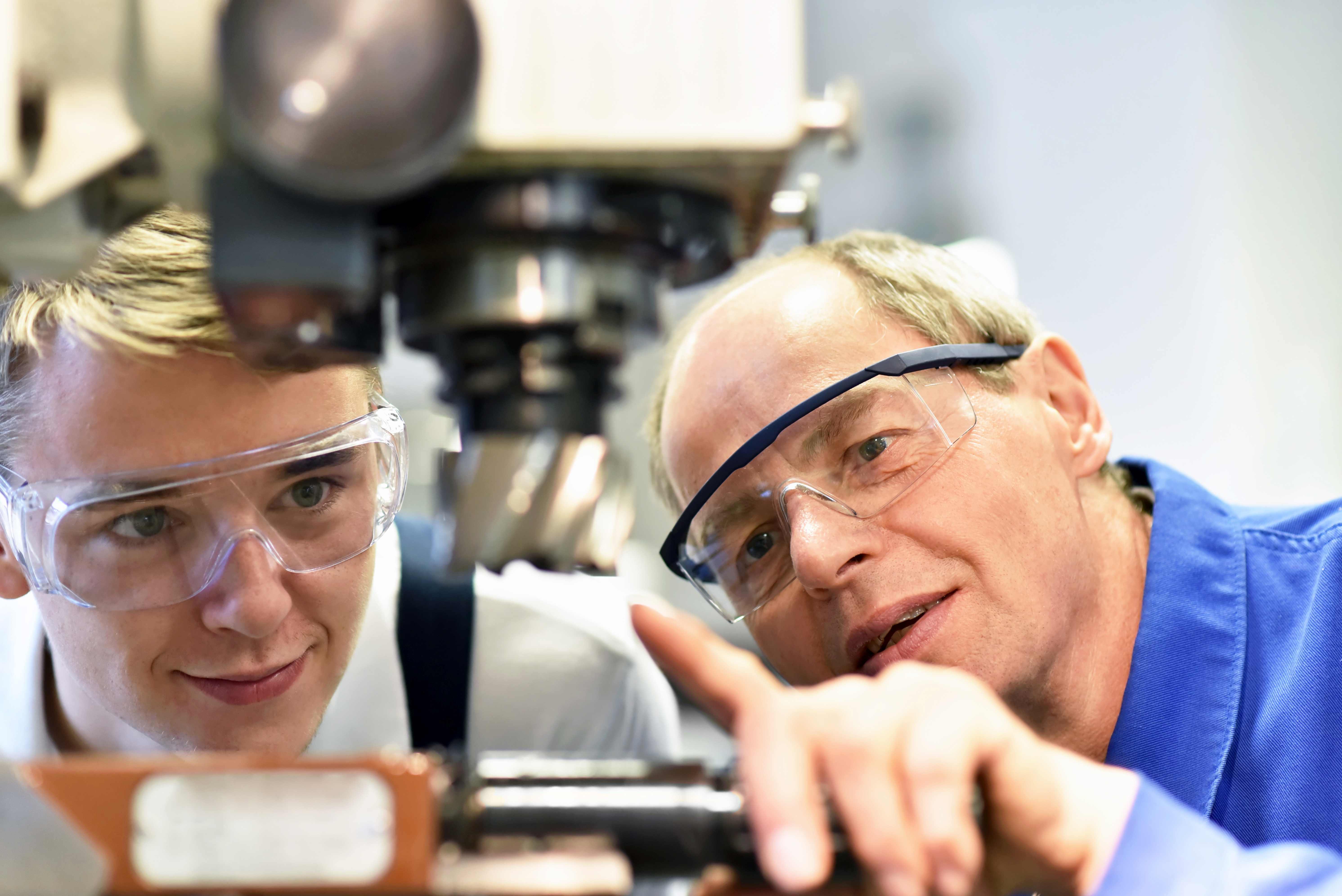  Jugendlicher und Lehrer an einer CNC Maschine