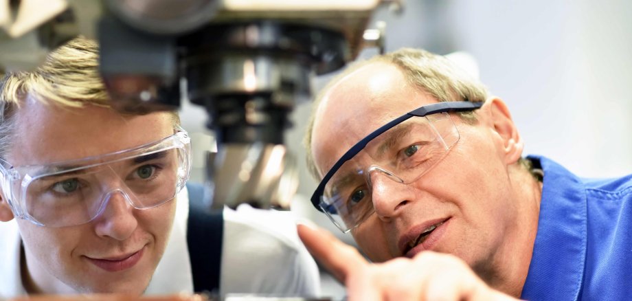  Jugendlicher und Lehrer an einer CNC Maschine