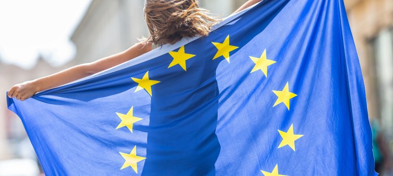 Junge Frau schwenkt EU-Flagge in einer Stadt
