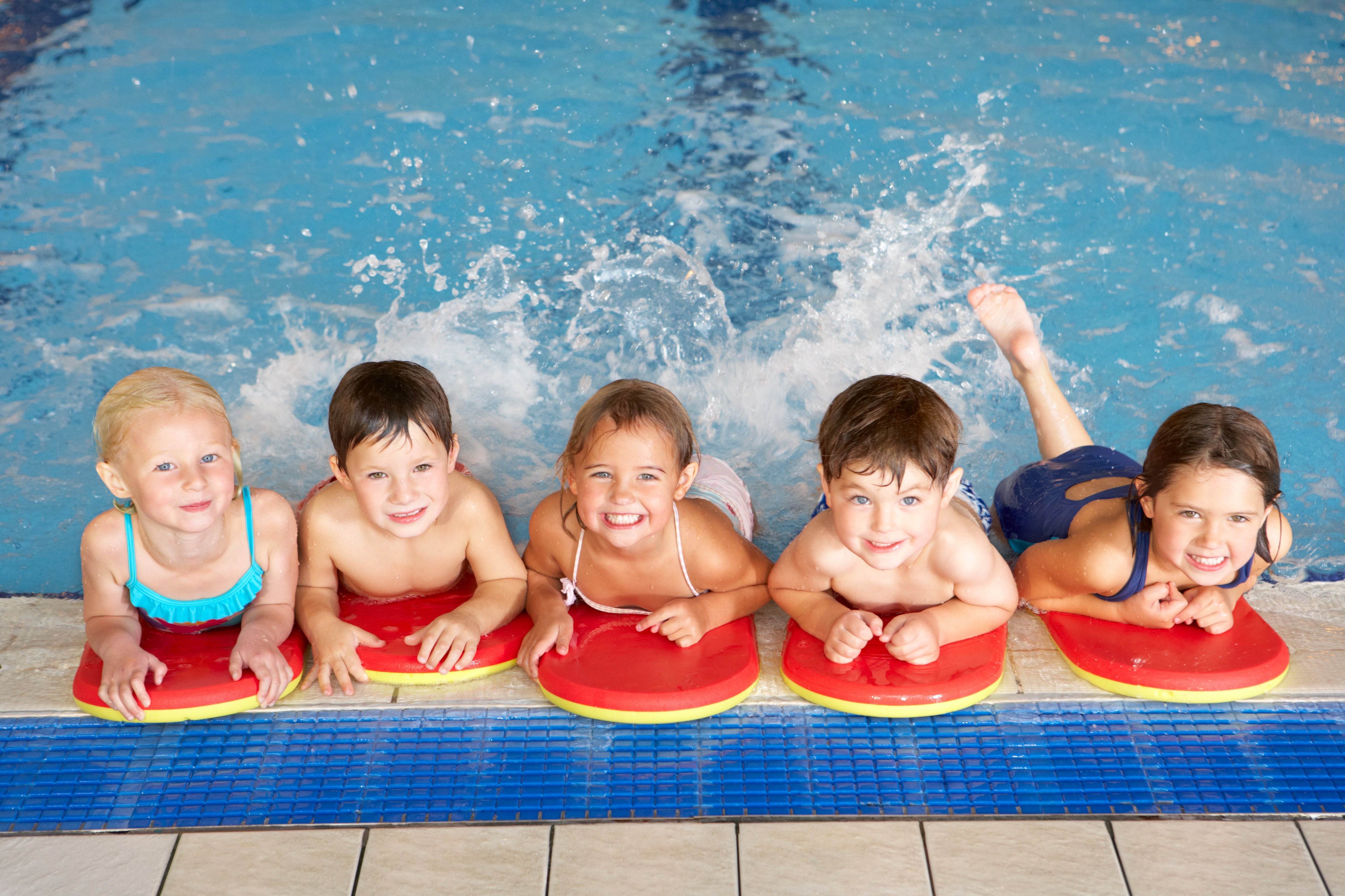 Das Bild zeigt eine Gruppe von Kindern am Beckenrand in einem Schwimmbad