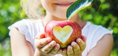 Mädchen hält einen Apfel Mädchen hält einen Apfel. Ein Herz ist in den Apfel geschnitzt.