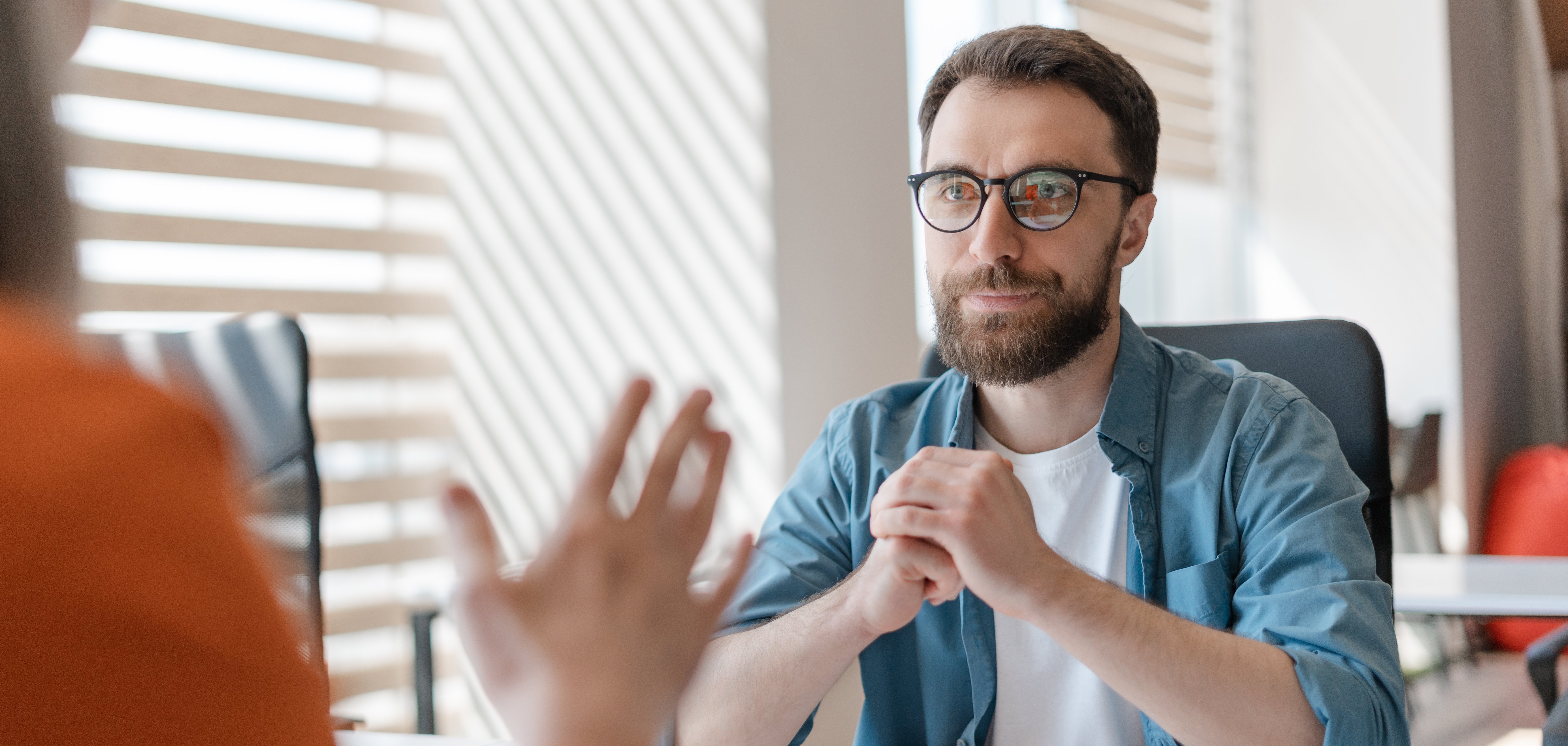 Ein Mann hört einer anderen Person in einer Beratungssituation zu.