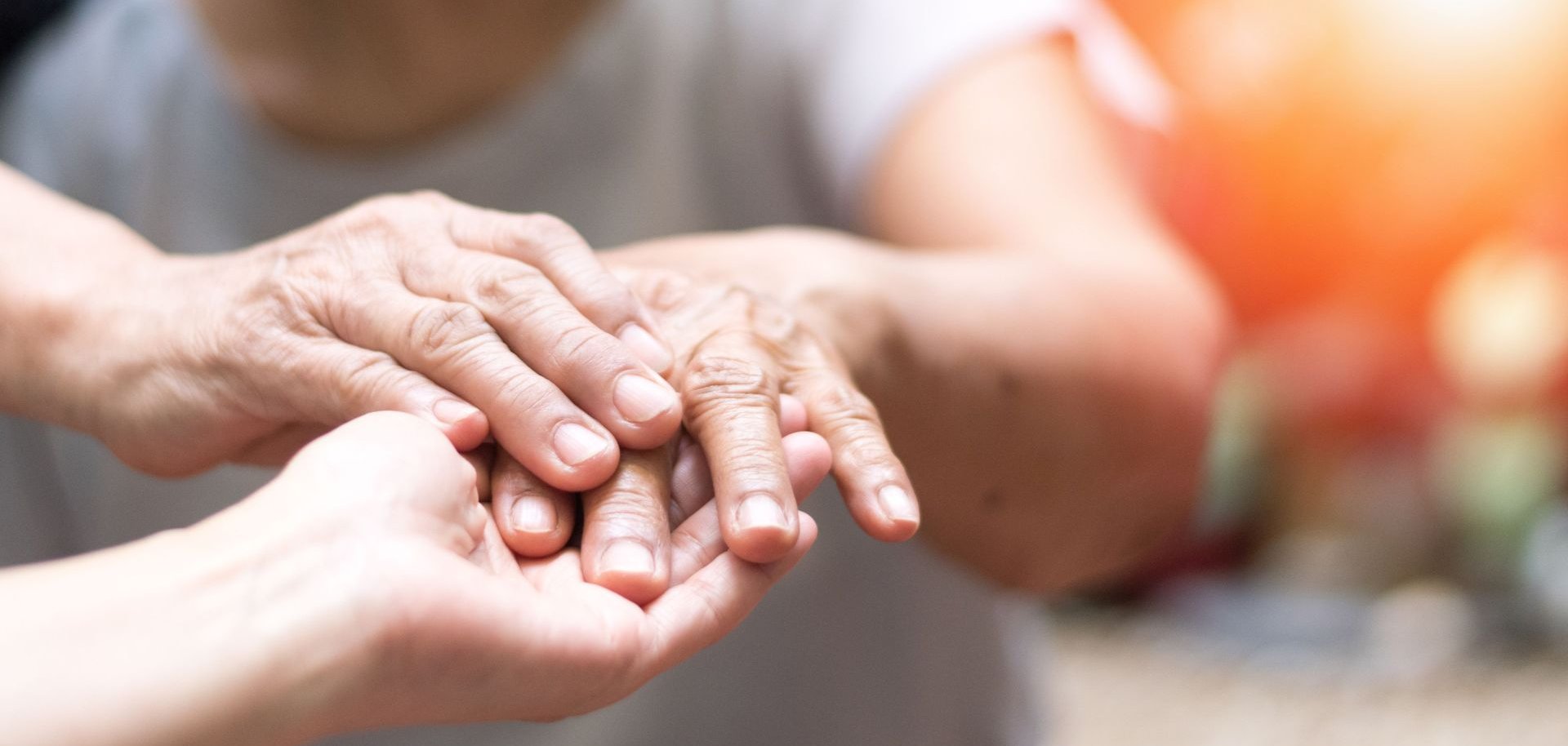 Ein paar Hände halten die Hand einer Seniorin.