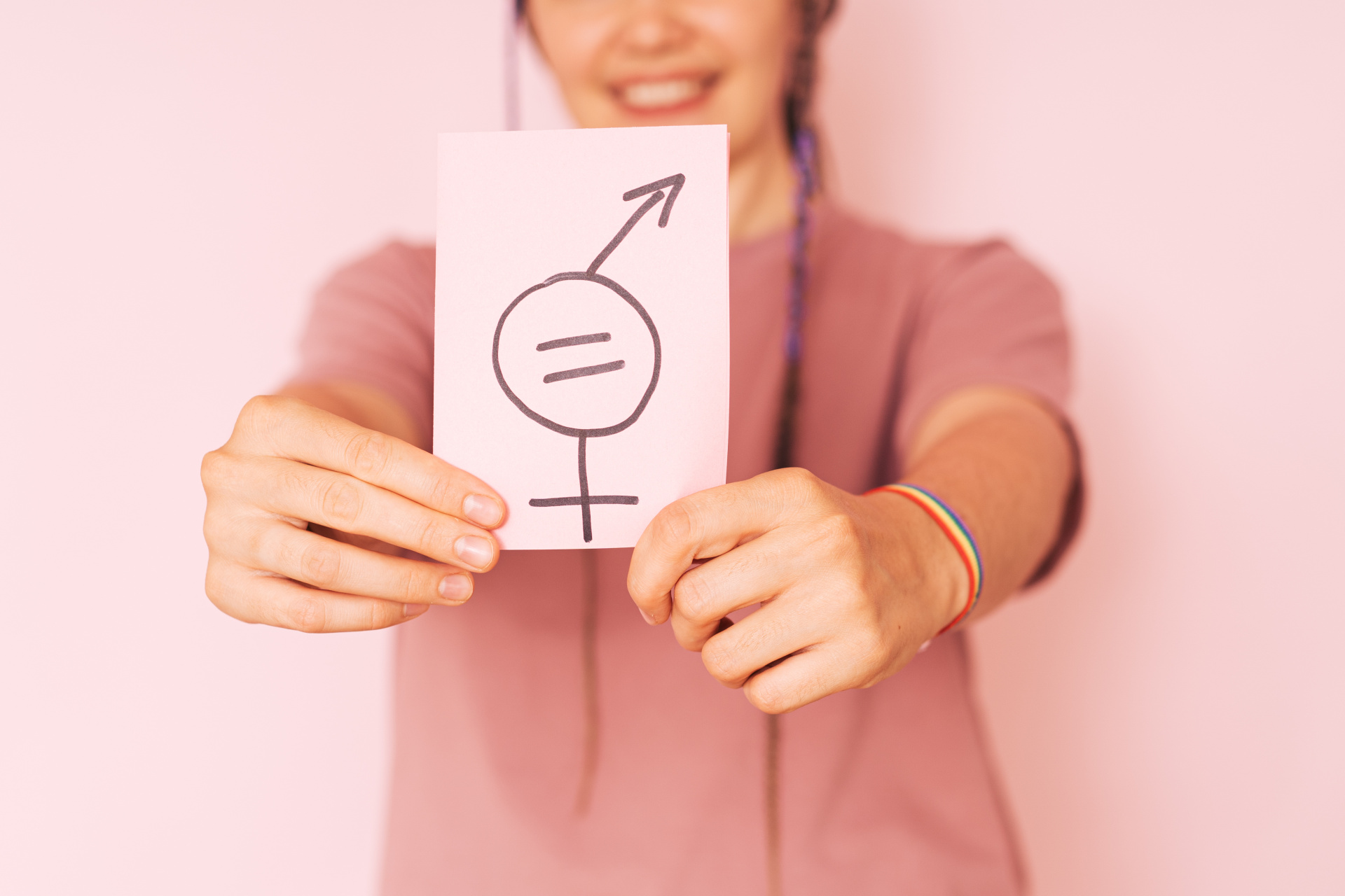 Girl holding paper with gender equality sign against pink background