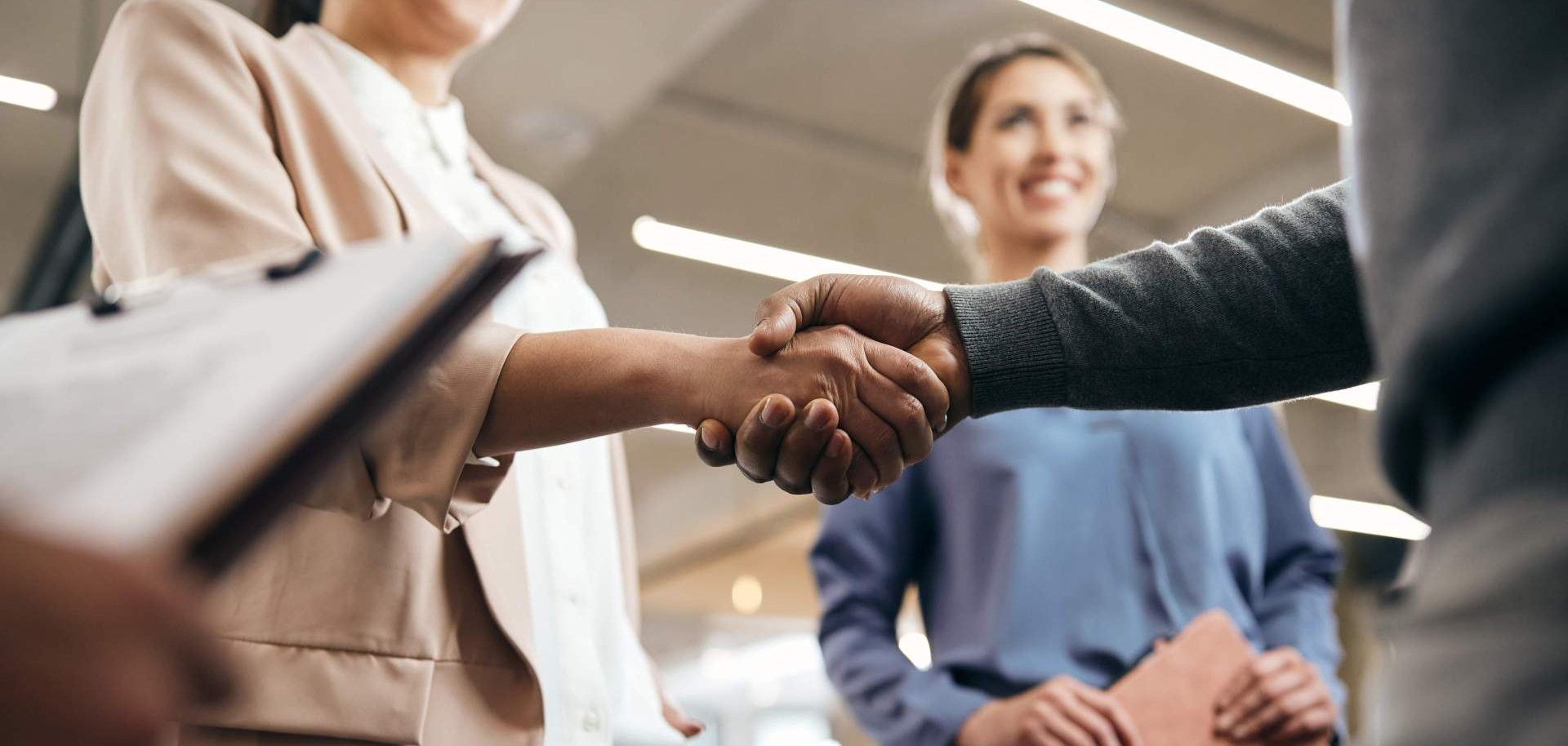 Zwei Menschen geben sich auf einer Job-Messe die Hand.