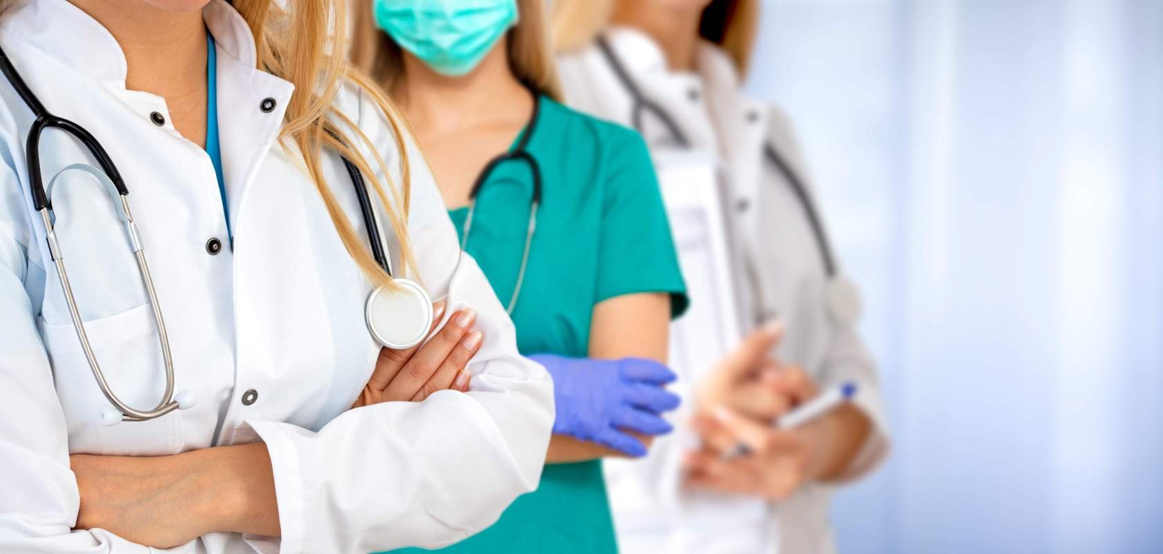 Vier medizinische Fachpersonen stehen mit verschränkten Armen nebeneinander.