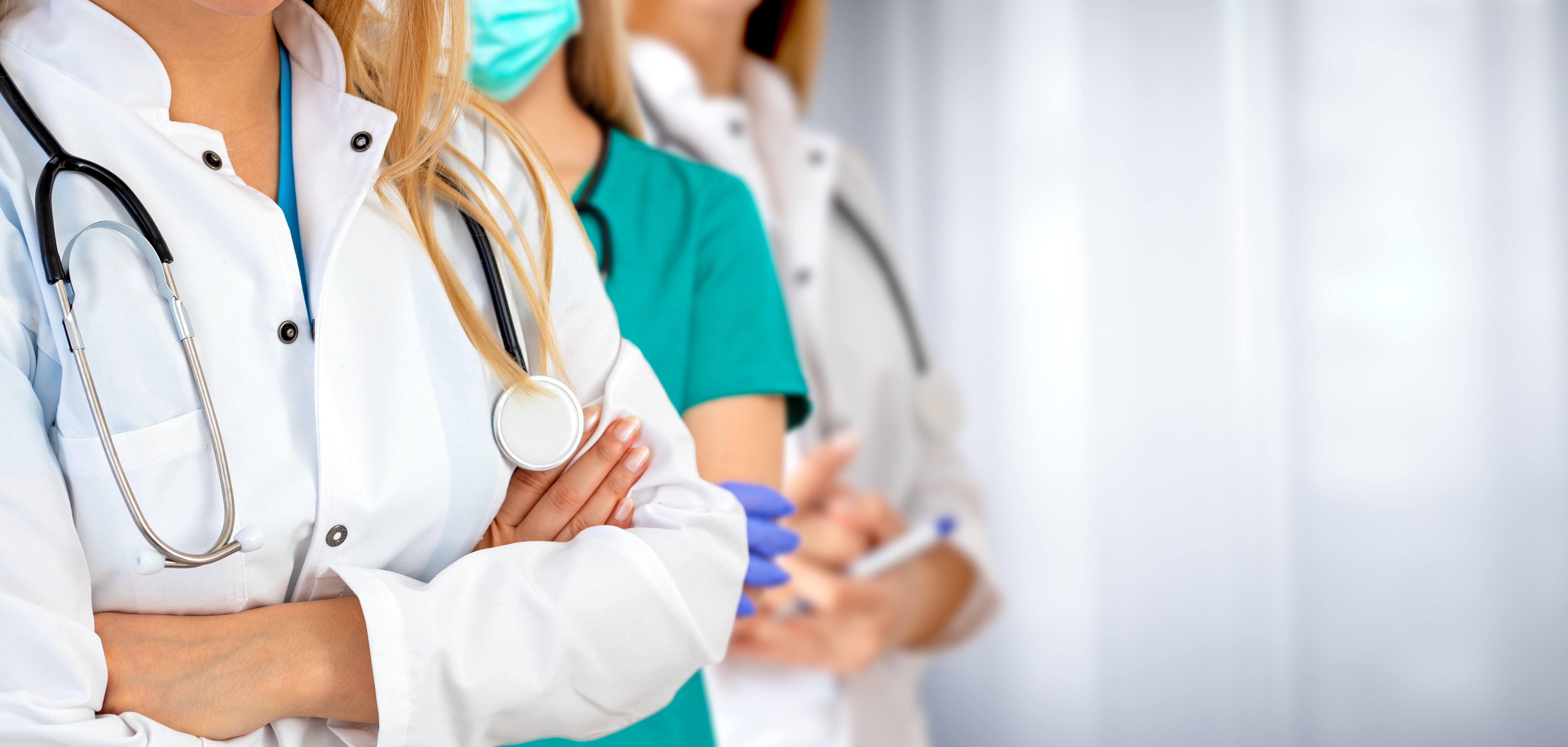 Eine Gruppe von Ärztinnen und Ärzten stehen mit verschränkten Armen nebeneinander.