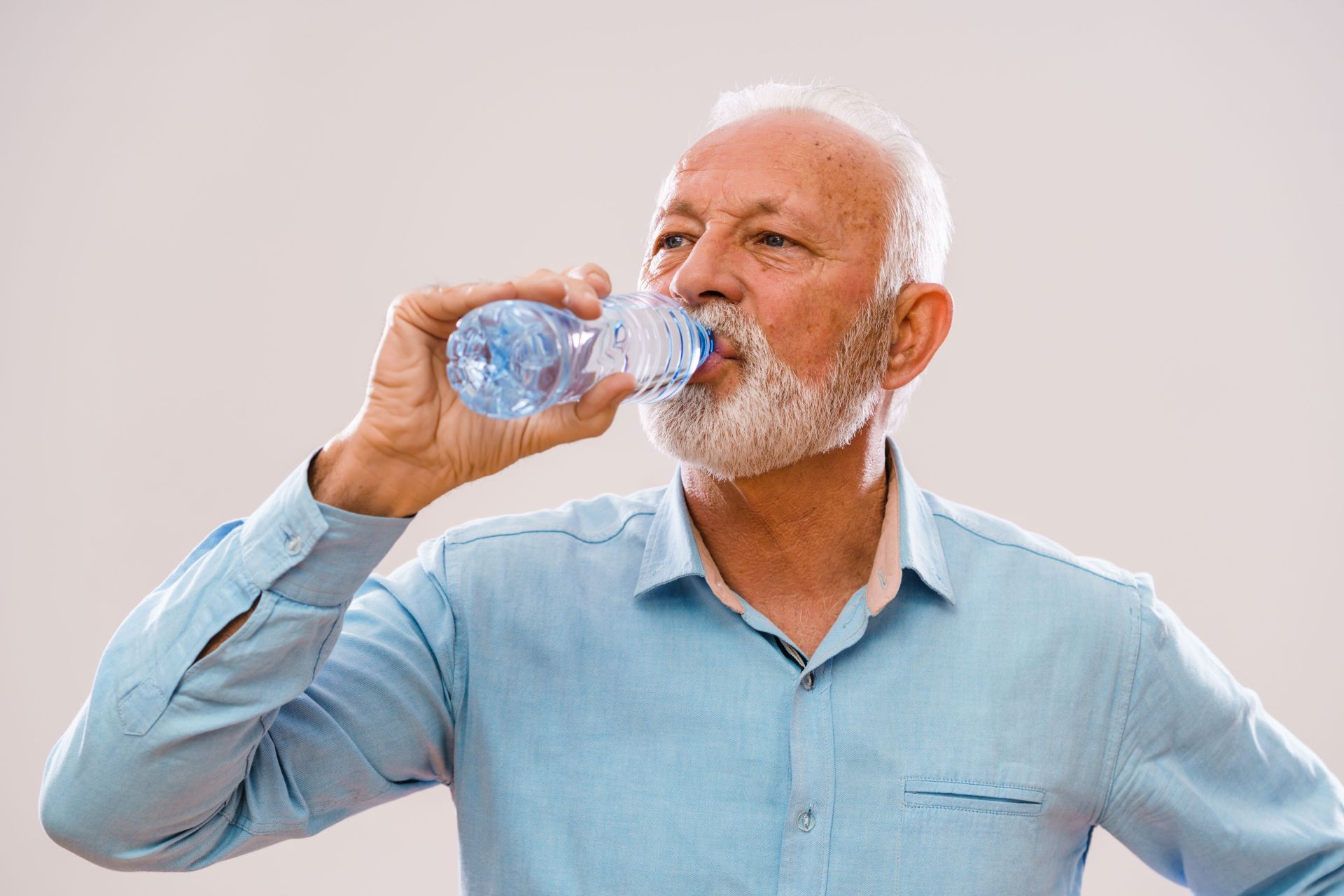 Ein älterer Mann trinkt Wasser aus einer Flasche.