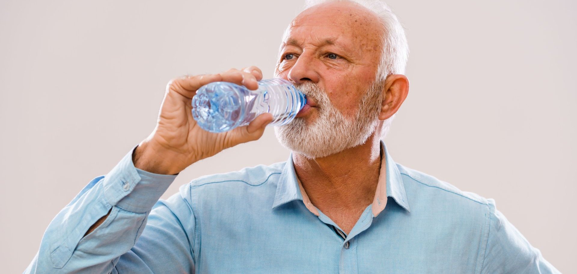 Ein älterer Mann trinkt Wasser aus einer Flasche.