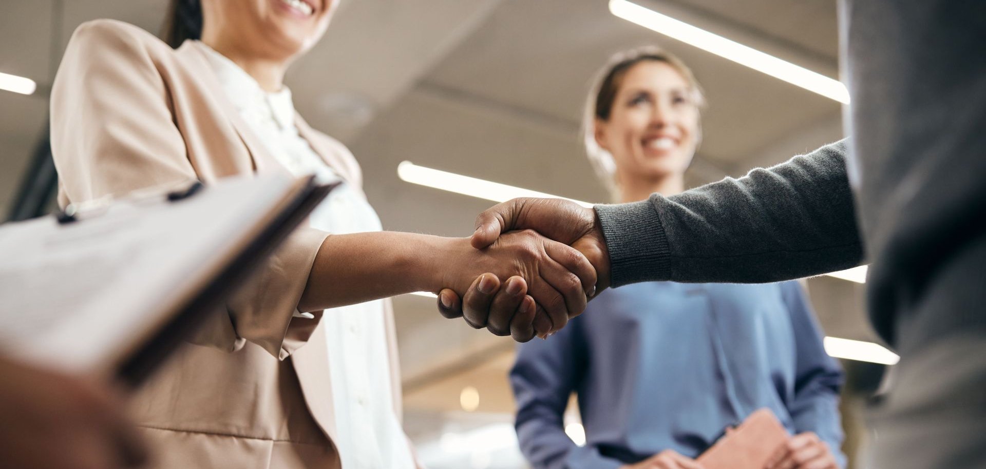 Zwei Menschen schütteln sich in einer Business-Umgebung die Hand.