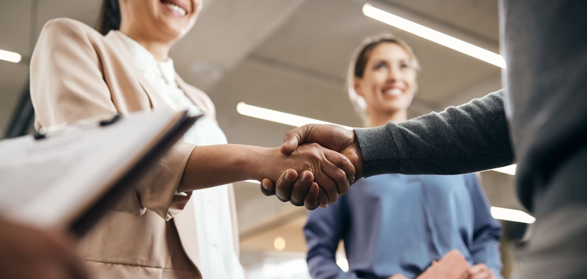 Zwei Menschen schütteln sich in einer Business-Umgebung die Hand.