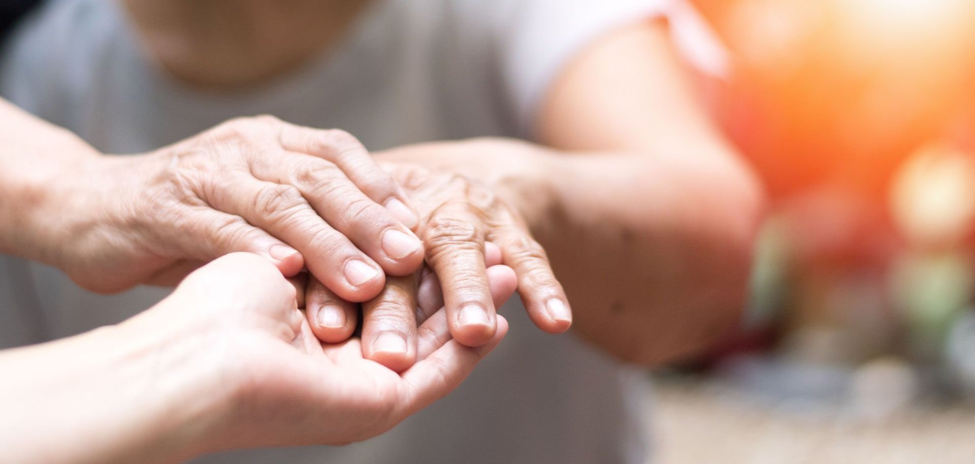 Eine Person hält die Hand einer älteren Person in den Händen.