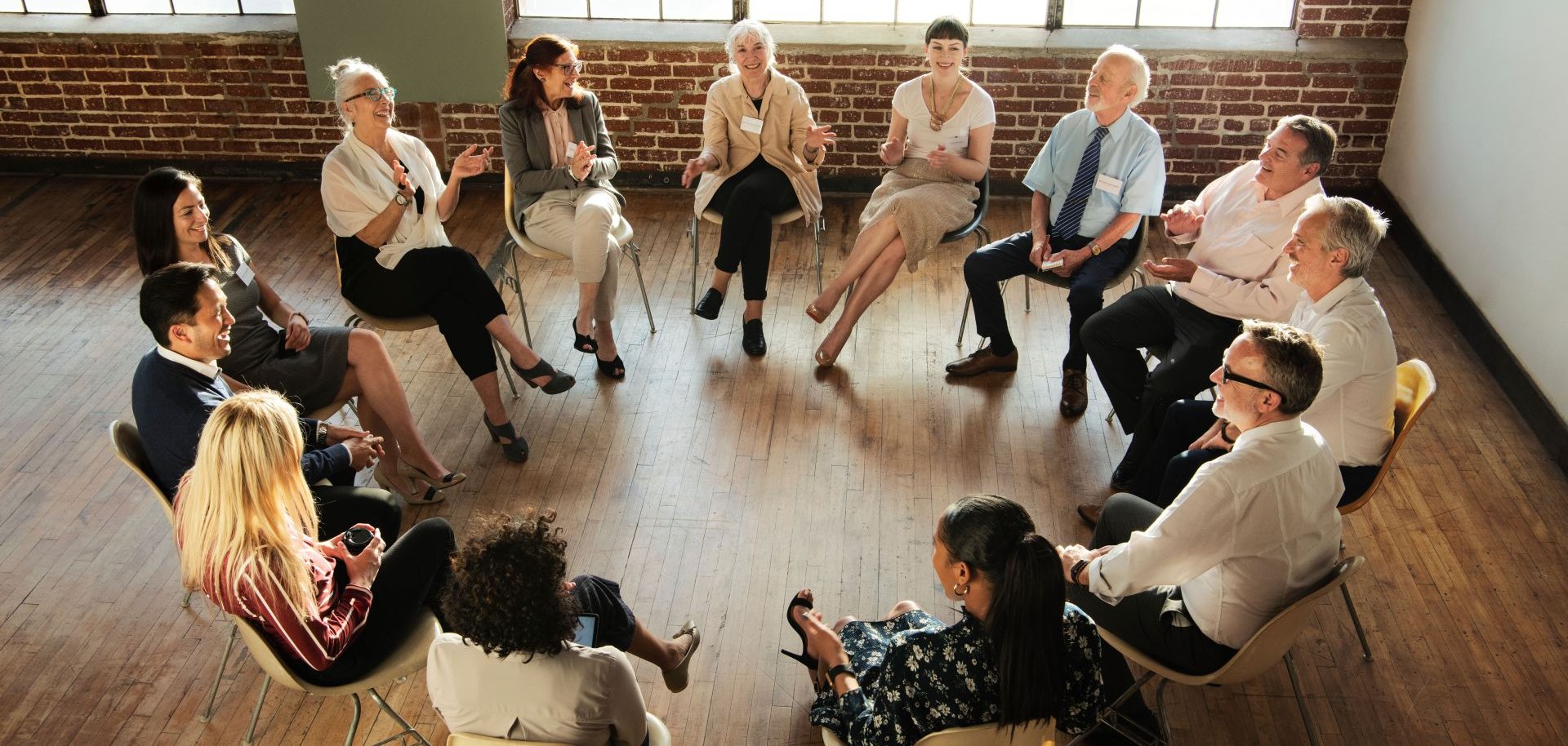 Mehrere Menschen sitzen in einem Stuhlkreis und reden miteinander.