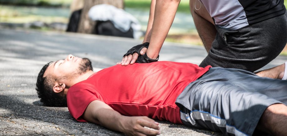 Ein Jogger reanimiert einen am Boden liegenden Mann.