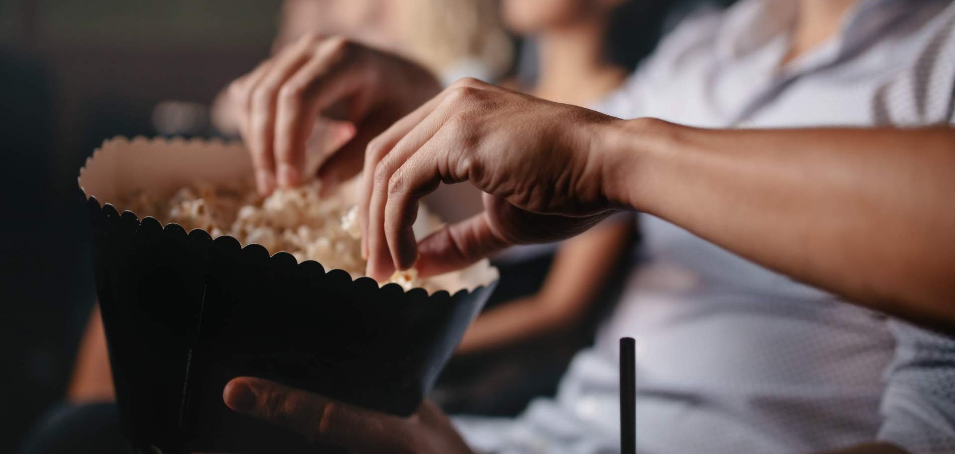 Abschlussveranstaltung Jahresprojekt Sterben Nahaufnahme von jungen Leuten, die im Kino Popcorn essen mit Fokus auf den Händen.
