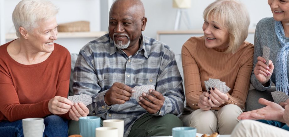 International group of cheerful elderly people chilling together, playing cards
