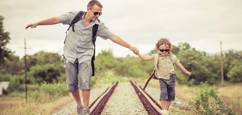 Novembergespräch EB Bensheim Ein Mann balanciert mit seinem Sohn an der Hand über Schienen.