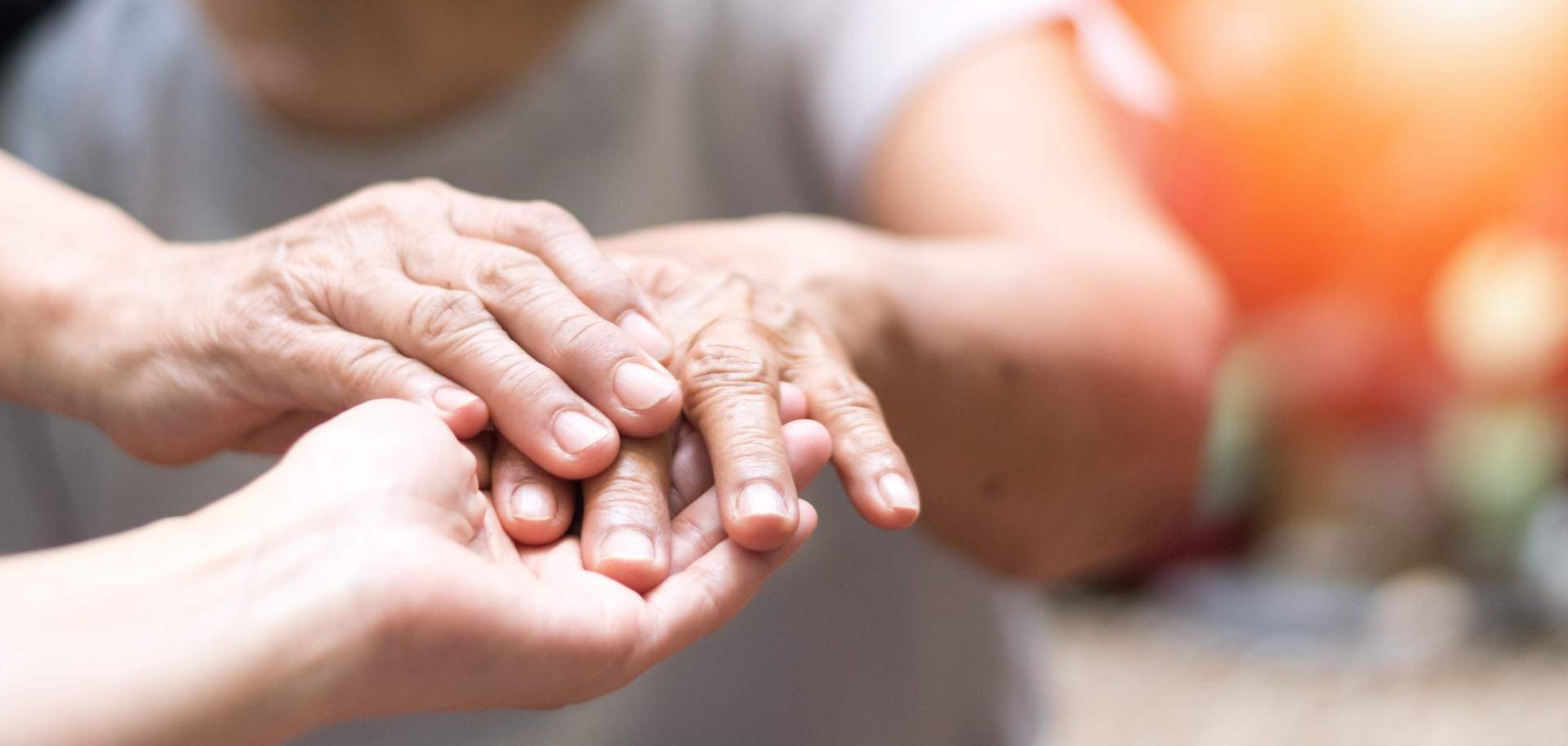 Eine Frau hält die Hand einer Seniorin in ihren Händen.
