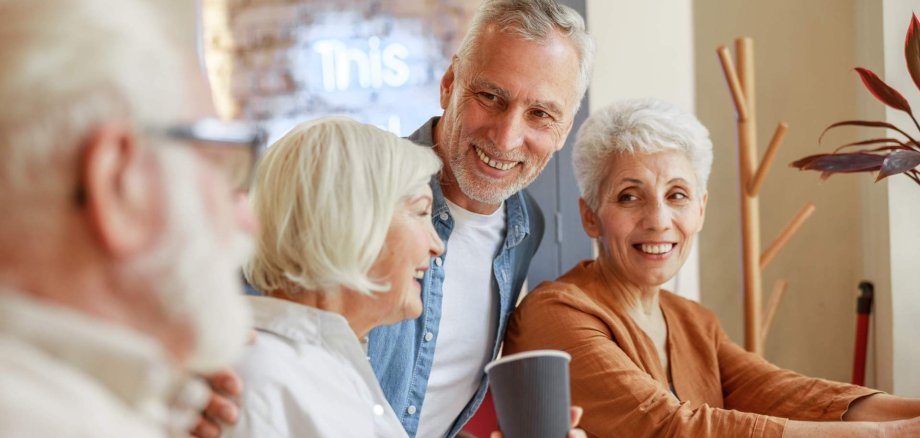 Eine Gruppe Seniorinnen und Senioren unterhalten sich gemeinsam.
