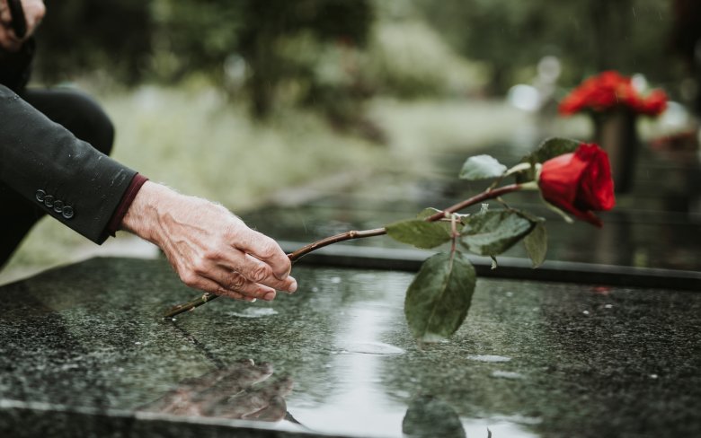 Senior legt Rose auf Grabstein